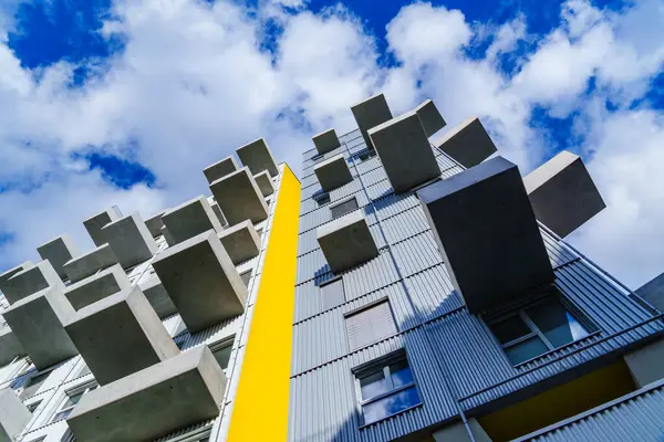 Beton balkonları ve parlak mavi gökyüzünün altında bulutlu sarı aksanı olan çağdaş yerleşim yerleri.