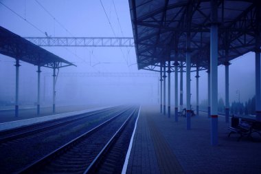 İstasyondaki boş platform ve sise giden raylar