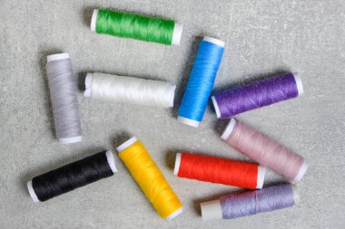 Çok renkli dikiş ipliklerine sahip makaralar gri beton arka plan