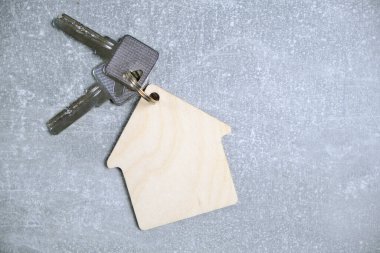 Anahtarlar ve anahtarlıklar beton zemin üzerinde ev biçiminde. Emlak satın alıp kiralama kavramı