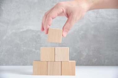 Laying out by hand a pyramid wooden cubes leading up.Concept growth and development