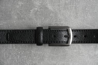 Black men leather belt with metal badge gray concrete background