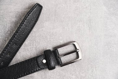 Black men leather belt with metal badge gray concrete background