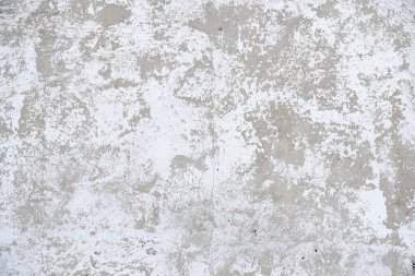 Old, gray concrete wall with peeling white paint