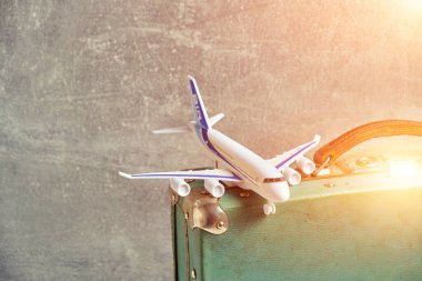 Old, vintage, retro suitcase and toy airplane in sunlight.Concept recreation and travel