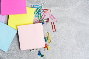Bundles paper stickers for writing notes and paper clips with stationery buttons gray concrete background