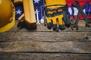 US flag, set construction tools and protective helmet wooden background.Concept for Labor Day first May