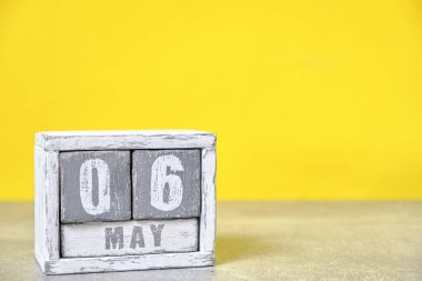 May 6, Wooden desktop calendar yellow background.Spring month depicted on cubes.Place for your ideas