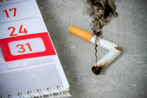 Black smoke coming from discarded cigarette.Background is calendar with 31st number marked.Concept for tobacco free day