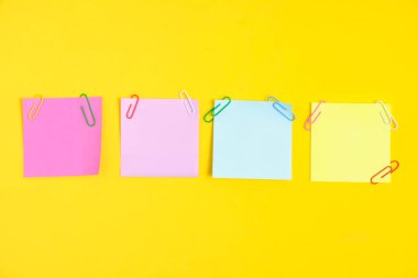 Colorful stickers for notes and paper clips yellow background