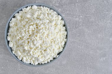Cottage cheese in plate gray concrete background, top view