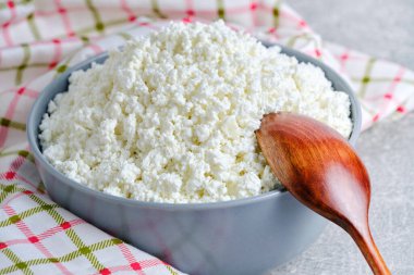 Homemade cottage cheese in glass bowl with wooden spoon background checkered towel