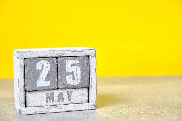 May 25 calendar made wooden cubes yellow background.With an empty space for your text