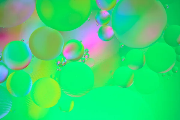 緑色の背景を持つ水面上の油円を持つ複数の色の抽象的な背景 — ストック写真
