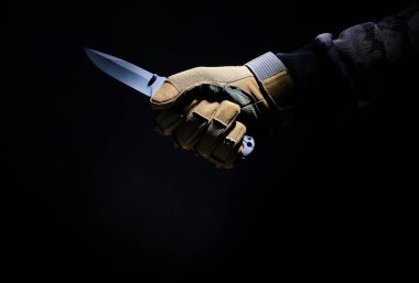 Siyah arka planda eldivenle elinde katlanan taktik bıçağı.