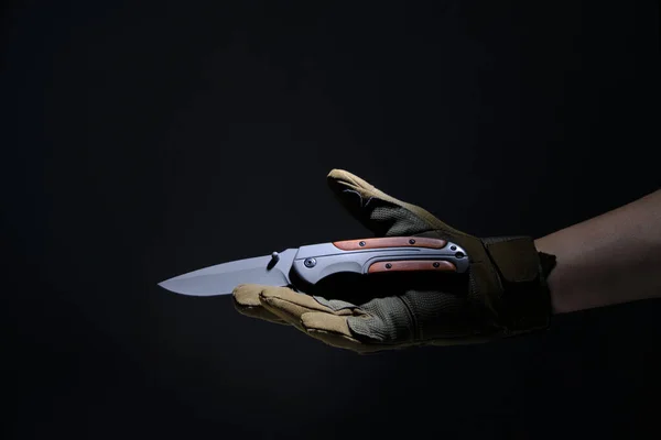 黒を背景に手袋を手に戦術的なナイフを折る — ストック写真