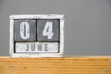 Gri arkaplanda rafta duran tahta küplerden yapılmış Haziran 04 takvimi. Metnin için boş bir boşluk var.