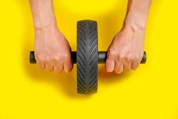 Hands holding onto press roller, playing sports on yellow background