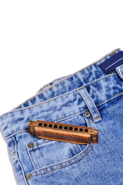 楽器のハーモニカはデニムパンツの上に横たわる — ストック写真