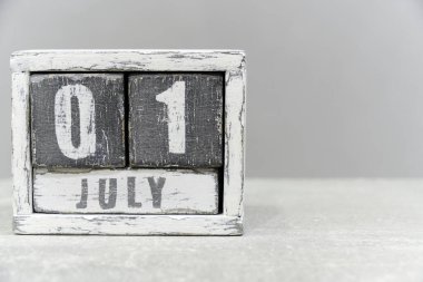 01 Temmuz takvimi, tahta küplerden yapılmış, gri arkaplan üzerinde. Metnin için boş bir boşluk var.