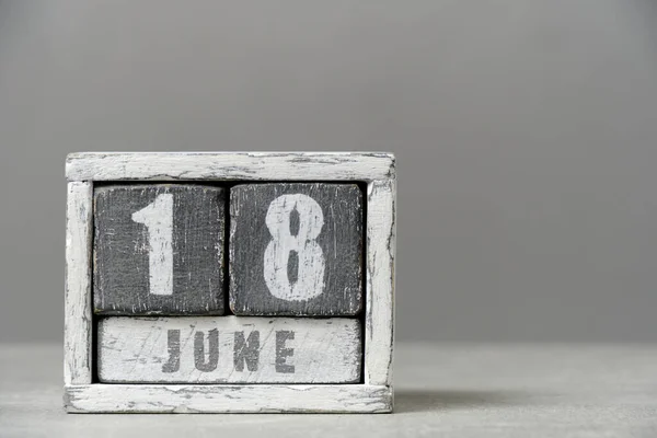 Calendar for June 18, made wooden cubes, on gray background.With an empty space for your text