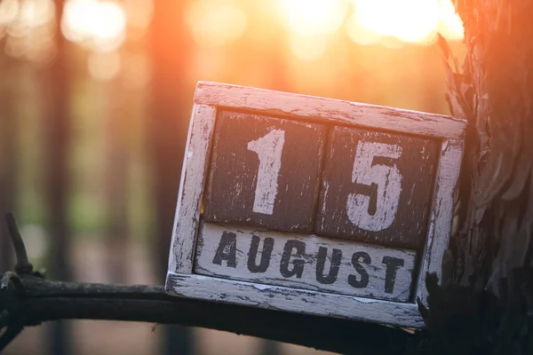 August 15, summer month, wooden calendar stands branch in forest against background bright sunset.Independence Day India