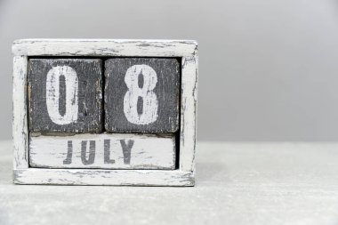 08 Temmuz takvimi, tahta küplerden yapılmış, gri arkaplan üzerinde. Metnin için boş bir boşluk var.