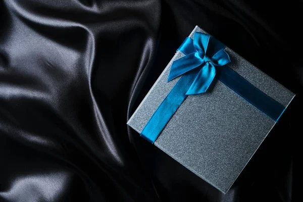 Ασημένιο Κουτί Δώρου Μπλε Τόξο Φόντο Μαύρο Μεταξωτό Ύφασμα — Φωτογραφία Αρχείου