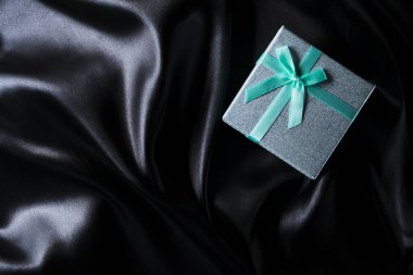 Siyah ipek kumaşlı, fiyonklu yeşil hediye kutusu.