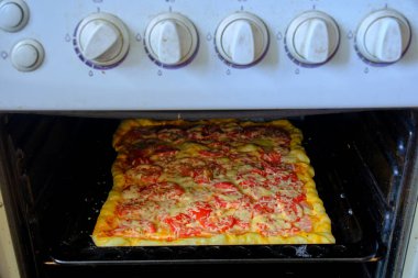 Domatesli pizza, sosis ve peynir fırında pişirilir.