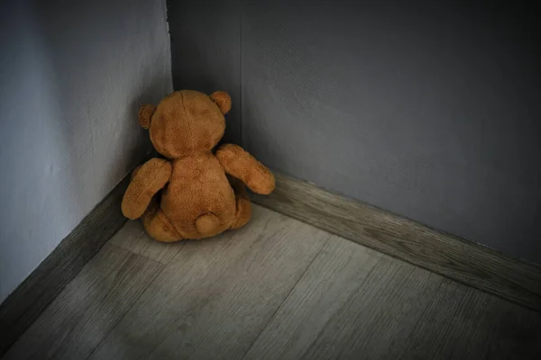 Teddy bear soft toy sitting corner room.Concept of domestic violence against children