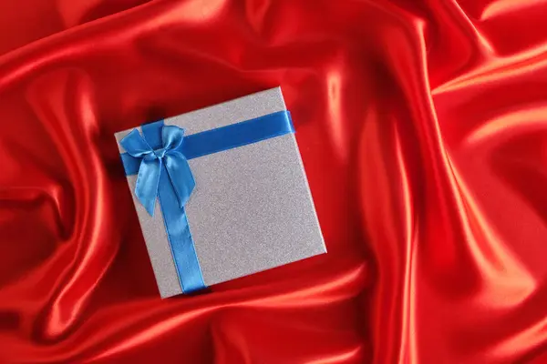 Coffret Cadeau Argent Avec Ruban Bleu Noeud Sur Tissu Rouge — Photo