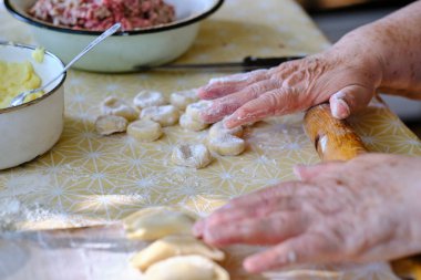 Hamuru rulo iğne ve hamur köftesi pişirmek için ellerle yuvarlıyor.