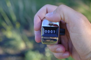 Elinizdeki yeşil arkaplandaki doğru sayım için manuel mekanik sayaç