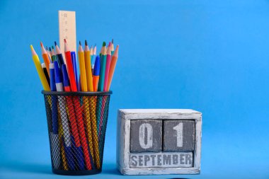 Kalem ve cetvelli düzenleyici, kırtasiye standı ve tarih 01 Eylül mavi arkaplan ile ahşap takvim