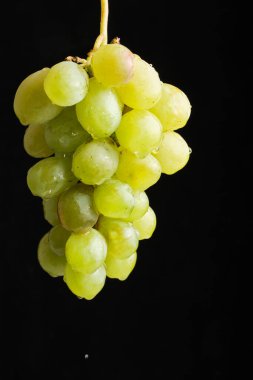 Asılı yeşil üzümler siyah arka plan