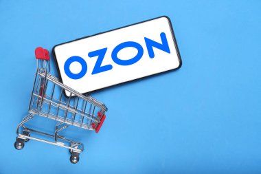 Kostanay, Kazakistan, 31 Ağustos 2023. OZON, OZON logosuna sahip en büyük Rus çevrimiçi perakendecisi. Alışveriş sepeti mavi arka plan. Çevrimiçi alışveriş kavramı..