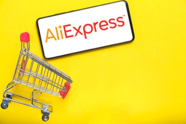 Kostanay, Kazakistan, 31 Ağustos 2023. Aliexpress logolu akıllı telefon, alışveriş sepeti sarısı arka plan. İnternetten alışveriş kavramı.