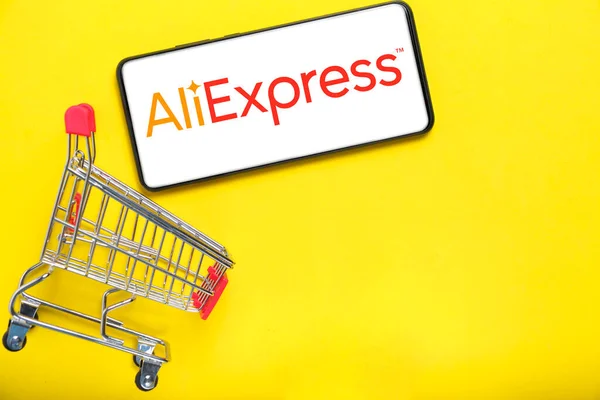 Kostanay, Kazakistan, 31 Ağustos 2023. Aliexpress logolu akıllı telefon, alışveriş sepeti sarısı arka plan. İnternetten alışveriş kavramı.