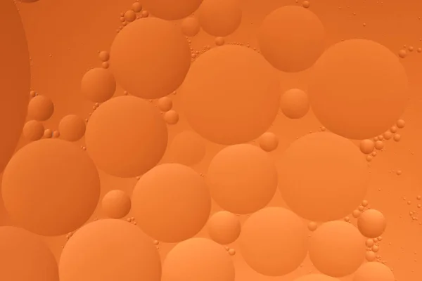 Macro photo with circles oil droplets water surface. Abstract orange background with oil bubbles