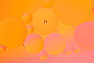 Su yüzeyinde yağ çemberleri olan soyut turuncu pembe arkaplan