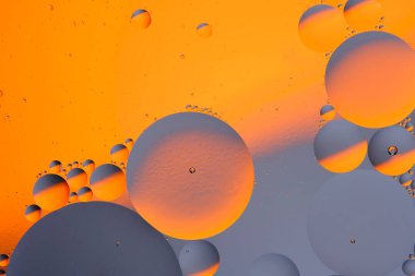 Soyut turuncu gri arkaplan, su yüzeyinde yağ daireleri var.