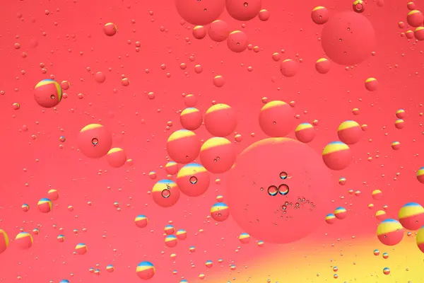 Macro photo with circles oil droplets water surface. Abstract yellow and red background with oil bubbles
