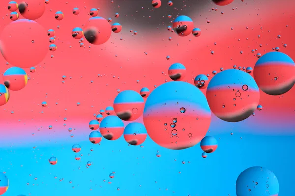 Macro photography with circles oil droplets water surface. Abstract with blue, black and red background with oil bubbles