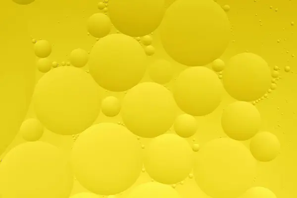 Macro photo with circles oil droplets water surface. Abstract yellow background with oil bubbles
