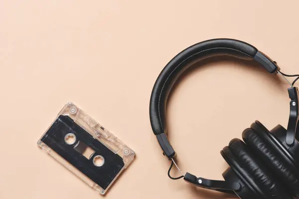 Headphones and an audio cassette beige retro background