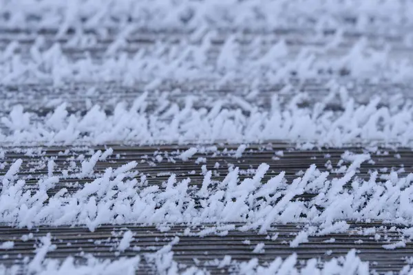 Old boards are covered with snow crystals and frost after severe frosts