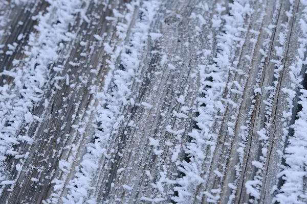 Old boards are covered with snow crystals and frost after severe frosts