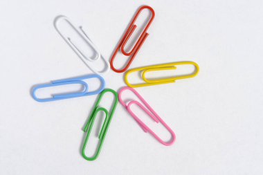 Multi colored paper clips are folded in shape star white background