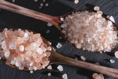 İki tahta kaşık pembe tuzla doludur.